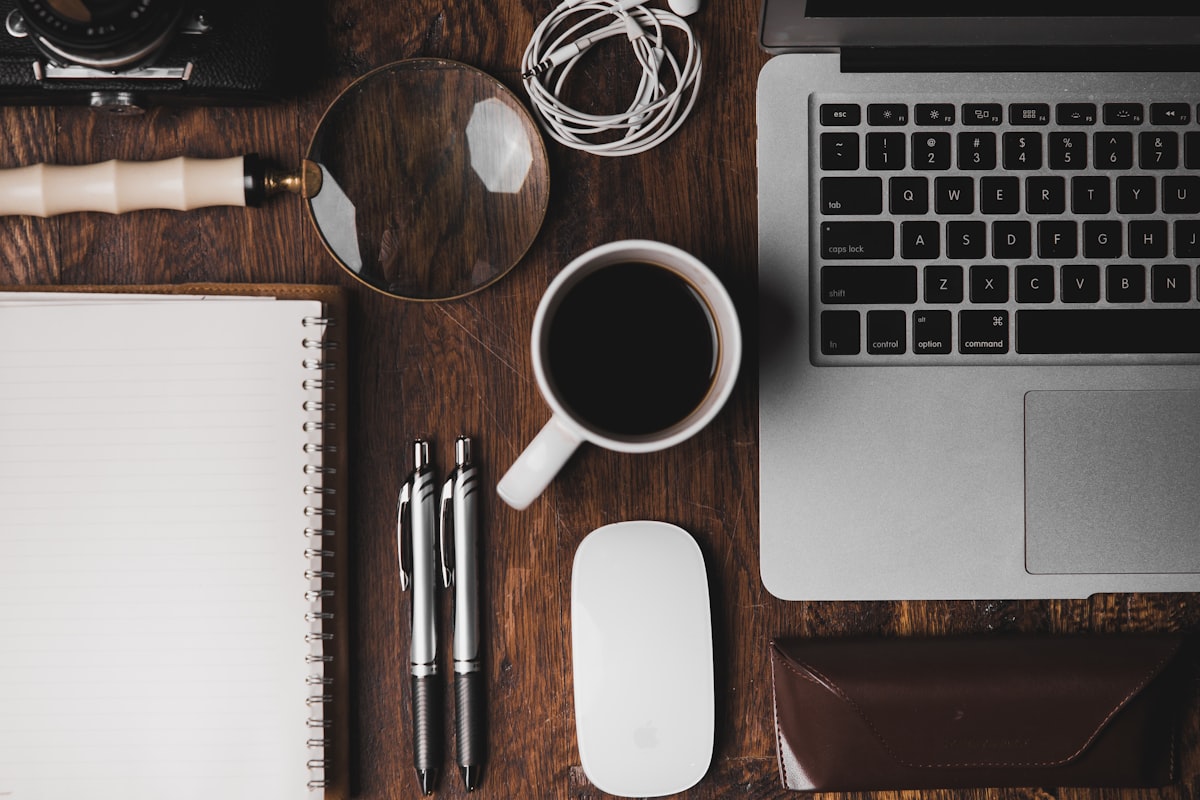 Bureau : ordinateur, carnet et loupe — la recherche de prospects au quotidien